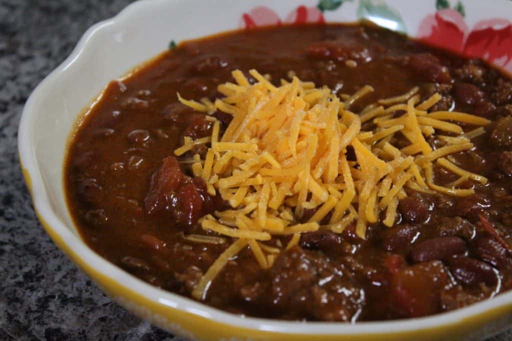 Bowl of chili with shredded Cheddar cheese on top. 