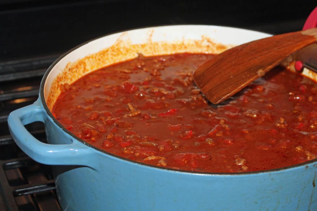 Blue 7 quart Dutch oven full of chili sitting on stove 