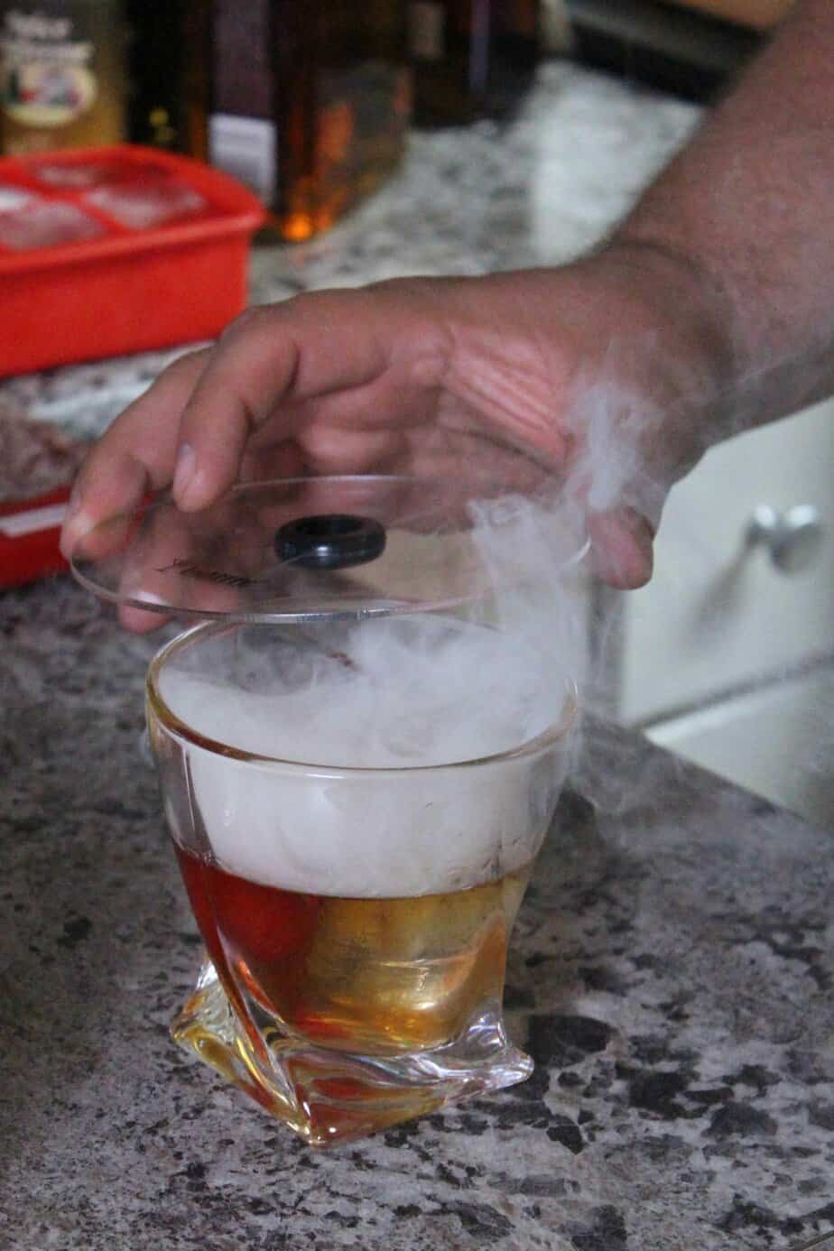 old fashioned cocktail in glass with smoke billowing from the top