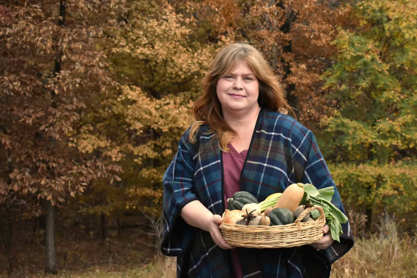 Dr. Niki Davis holding a basket of fruit standing outside in the fall.